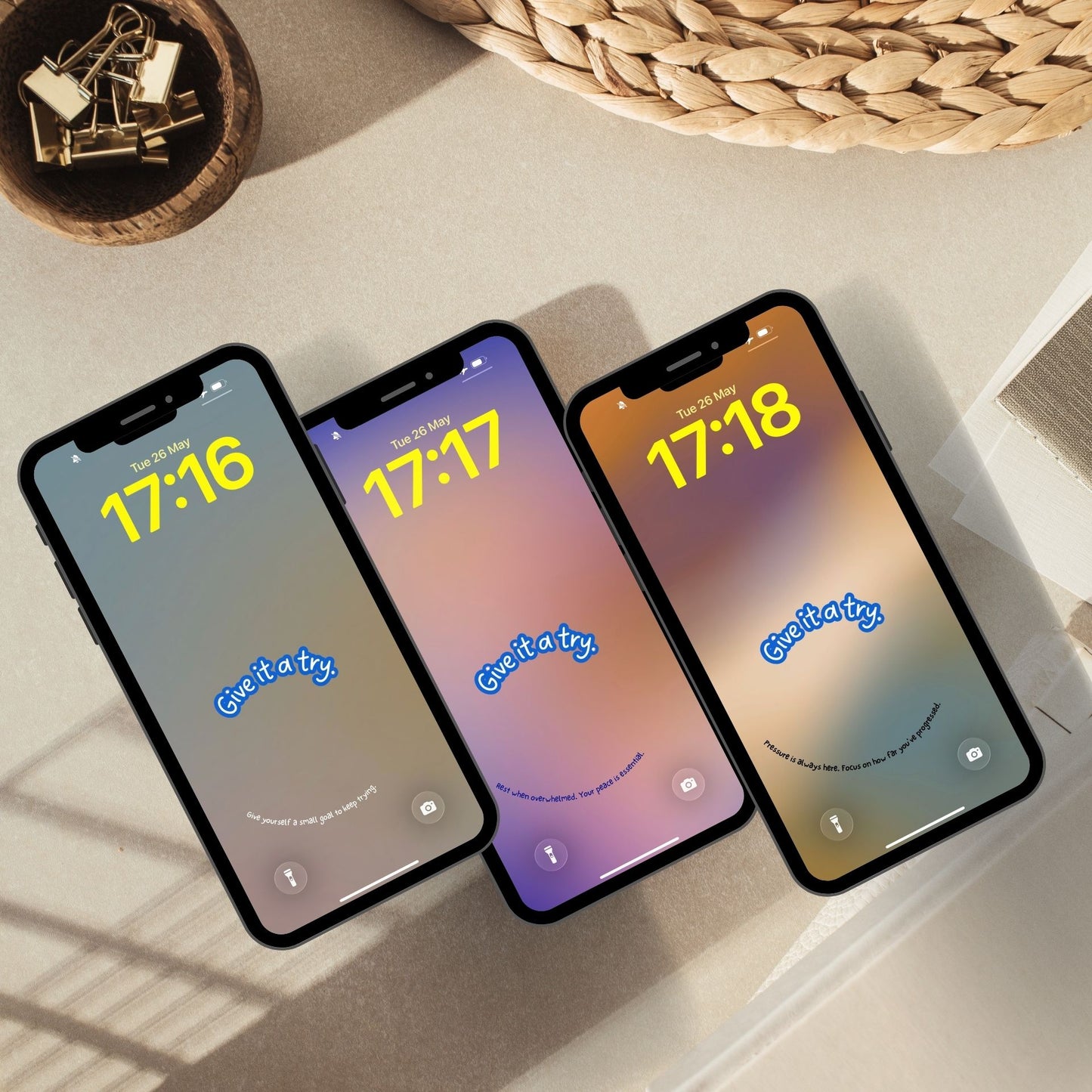Three phone mockups fanned out at an angle showing inspirational phone wallpapers in soft gradient tones. Each phone has a short curved affirmation along the bottom.